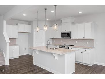 Bright kitchen features white cabinets, granite countertops, stainless appliances, and pendant lighting at 22 Van Winkle St, Lillington, NC 27546