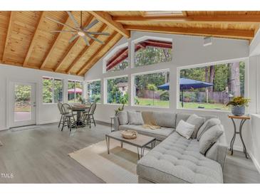 Bright sunroom features vaulted ceilings, comfy seating, and views of the backyard at 5814 Windham Dr, Raleigh, NC 27609