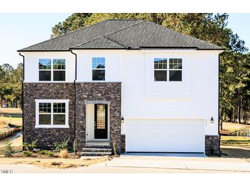 Inviting new construction home with stone and siding exterior, a garage, and manicured landscaping at 556 Barbour Farm Ln, Four Oaks, NC 27524