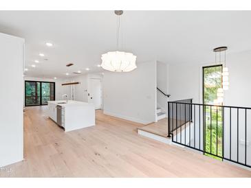 Open concept living space features hardwood floors, modern light fixtures, and a kitchen island at 2123 Brewer St, Raleigh, NC 27608