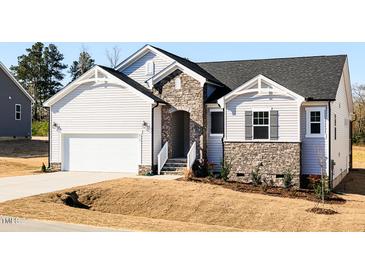 Charming home featuring stone accents, white siding, an attached garage, and fresh landscaping at 472 Barbour Farm Ln, Four Oaks, NC 27524