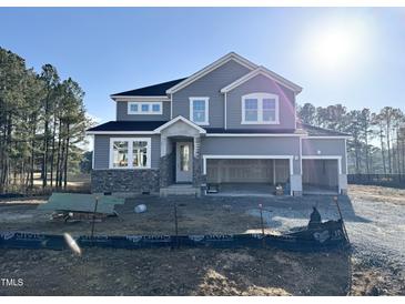 Two-story gray house with stone accents and a three-car garage at 536 Barbour Farm Ln, Four Oaks, NC 27524