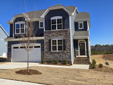 Two-story house with gray siding, stone accents, and a white garage door at 1109 Prominence Dr., Homesite 17, Durham, NC 27712