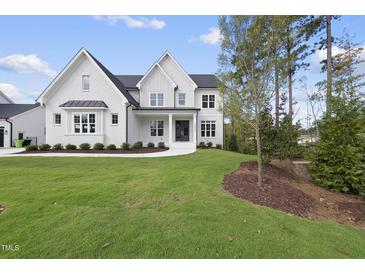 Elegant, modern two-story home featuring white brick, black roof, and lush green lawn at 2506 Silas Peak Ln, Apex, NC 27523