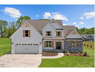 Charming two-story home featuring a white facade, stone accents, wooden shutters, and a neatly manicured lawn at 2568 Lassiter Rd, Four Oaks, NC 27524
