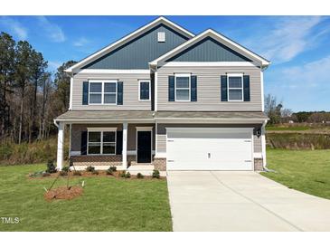 Charming two-story home features gray siding and black shutters with a well manicured lawn at 116 Bristow Ct # 49, Four Oaks, NC 27524