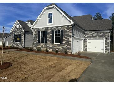 New construction home features stone accents, a two-car garage and beautifully maintained front lawn at 135 Ironwood Blvd # 49, Youngsville, NC 27596