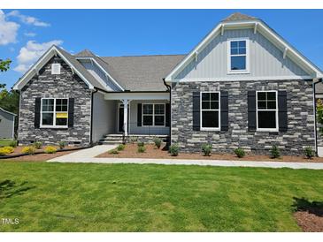 Charming stone-accented home with well-manicured lawn, sidewalk, and inviting covered porch at 135 Ironwood Blvd # 49, Youngsville, NC 27596