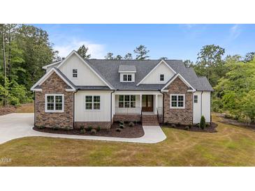 Charming two-story home with stone and white siding, complemented by a lush, landscaped front yard at 225 Whistlers Cv, Louisburg, NC 27549