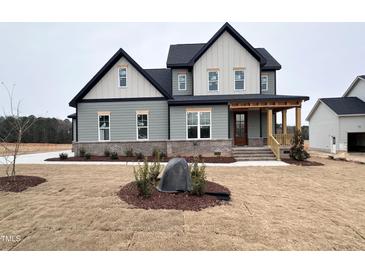 Two-story farmhouse with gray siding, a covered porch, and a landscaped yard at 100 Firefly Ln, Louisburg, NC 27549