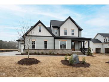 New construction two-story home with gray siding, black trim, and professionally landscaped front yard at 100 Firefly Ln, Louisburg, NC 27549