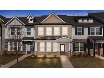 Charming townhome with covered porch, brick accents, neutral siding, and well-maintained landscaping at 953 Alma Railway Dr, Wake Forest, NC 27587