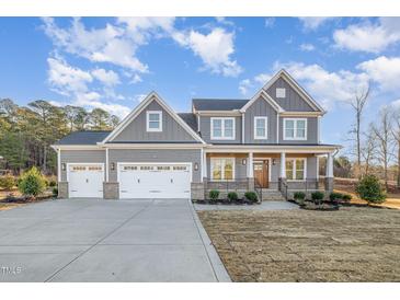 Charming two-story home with gray siding, a three-car garage, and a welcoming front porch at 649 Riverwood Dr, Clayton, NC 27527