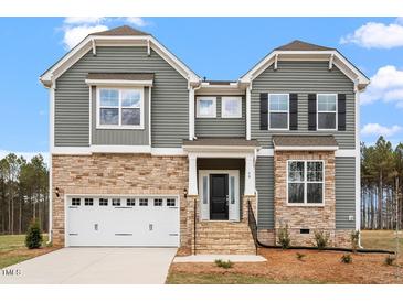 Inviting two-story home featuring stone accents, gray siding, well-manicured lawn, and an attached two-car garage at 90 Bold Dr, Youngsville, NC 27596