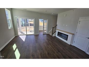 Bright living room with dark floors, sliding glass doors, and modern fireplace at 1349 Bessie Ct, Wake Forest, NC 27587