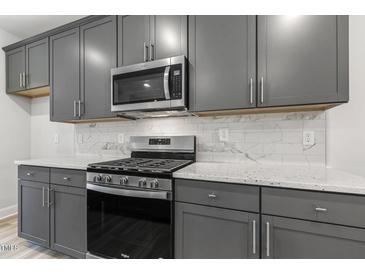 Well-equipped kitchen features gray cabinets, stainless steel appliances, and elegant white countertops and backsplash at 484 Traditions Grande Blvd # 29, Wake Forest, NC 27587