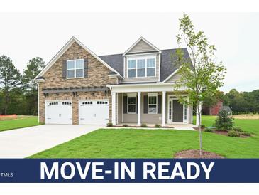 Move-in ready two-story house with stone and siding, two-car garage, and landscaped lawn at 138 Abingdon Farms Dr, Selma, NC 27576