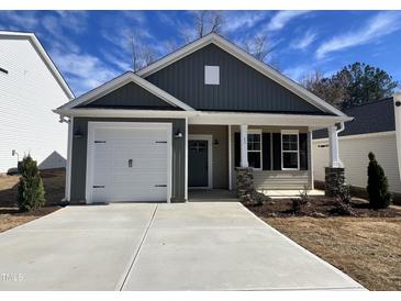 Charming single-story home featuring a one-car garage and covered front porch with stone accents at 23 S Mistflower St, Clayton, NC 27520
