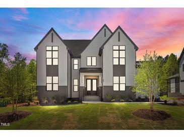 Striking exterior showcasing a modern two-story home with black-framed windows and lush green lawn at dusk at 65 Cherry Bark Dr, Youngsville, NC 27596