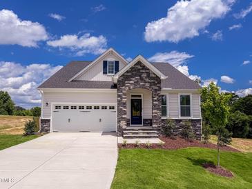 Charming home featuring a stone archway, two-car garage, and a well-manicured lawn at 85 Claude Creek Way, Smithfield, NC 27577