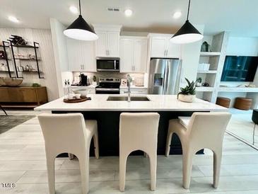Bright kitchen features a spacious island with counter seating, stainless steel appliances and modern pendant lighting at 2117 Opulent Oaks Ln # 15, Durham, NC 27713