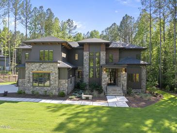 Stunning home featuring a stone and modern facade, professional landscaping, and a welcoming entrance at 7640 Falls Creek Ln, Raleigh, NC 27614