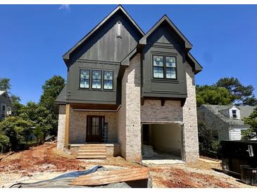 An exterior view of a two-story home featuring a brick facade, dark trim, and an attached garage at 627 Georgetown Rd, Raleigh, NC 27608