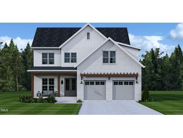 Charming two-story white brick home with attached two-car garage and a beautifully landscaped front yard at 204 E Whitaker Mill Rd, Raleigh, NC 27608