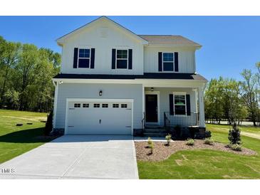 Charming two-story home with a covered front porch, an attached garage, and professionally landscaped lawn at 235 Grand Griffon Way, Lillington, NC 27546