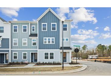 Charming new construction townhome with blue accents and inviting curb appeal on a sunny day at 1170 Holding Village Way, Wake Forest, NC 27587