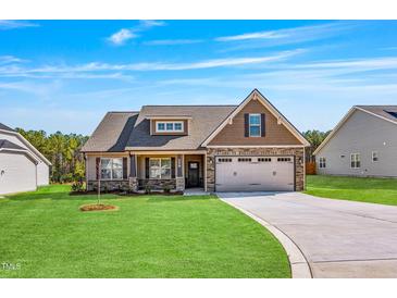 Charming single-Gathering home with a manicured lawn, stone accents, and a two-car garage at 258 Thistle Ct, Sanford, NC 27332