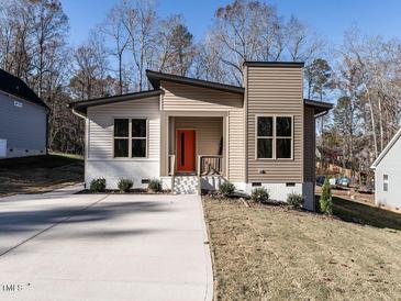Modern home with unique design elements, neutral siding, and a vibrant orange front door at 173 Nashua Dr, Louisburg, NC 27549