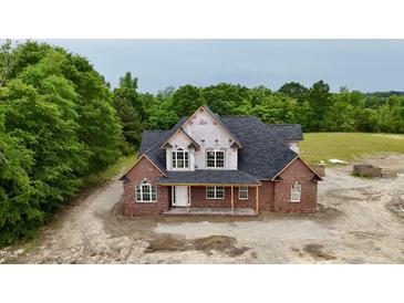 New two-story brick home with a dark roof and covered porch nestled on a wooded lot at 6352 River Rd, Fuquay Varina, NC 27526