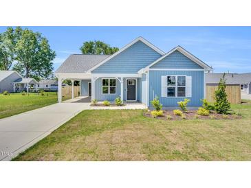 Charming blue home featuring a covered entrance, well-manicured lawn, and inviting curb appeal at 306 E Godwin St, Dunn, NC 28334