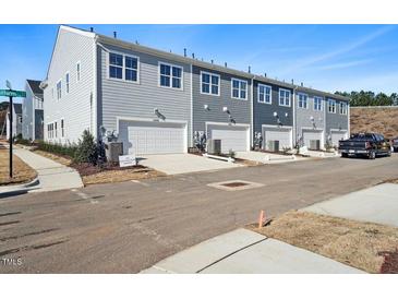 Modern townhomes featuring attached garages and neutral color schemes on a street with parking at 605 Hyperion Aly, Wake Forest, NC 27587