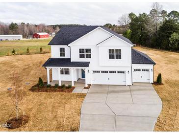 New construction home with a three-car garage, white siding, dark roof, and covered porch at 7417 Prato Ct, Wendell, NC 27591