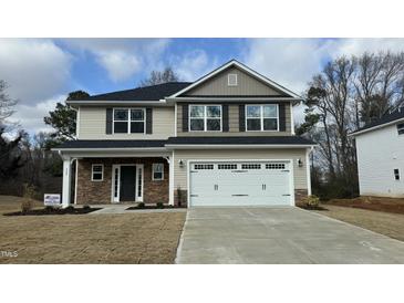 Charming two-story home with stone accents, a two-car garage, and a well-manicured lawn at 225 Hopewell Branch Ct, Smithfield, NC 27577