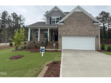 Charming two-story home with brick accents, a covered porch, and well-manicured landscaping at 145 Green Haven Blvd # 83, Youngsville, NC 27596