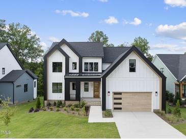 New construction home with modern farmhouse design, detailed trim, manicured lawn and wood garage door at 205 Red Cardinal Ct, Youngsville, NC 27596
