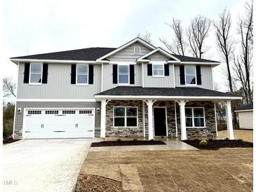 Charming two-story home with gray siding, a two-car garage, and a welcoming front porch at 31 Capeside Ct, Lillington, NC 27546