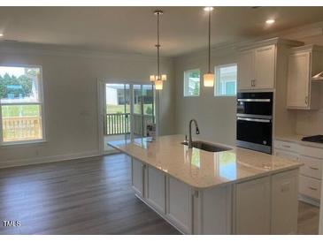Modern kitchen features an island with white countertops and stainless steel appliances at 1528 Maelyn Way, Fuquay Varina, NC 27526