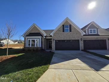Charming new construction home boasts a brick facade, a two-car garage, and a well-manicured lawn at 2080 Harris Farm Ct, Burlington, NC 27215