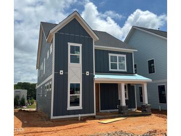 New two-story home featuring blue siding, a covered porch with stone accents and bright white window frames at 2412 Adrift Road, Fuquay Varina, NC 27526