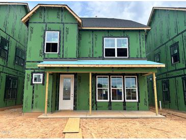 New construction home featuring green weather barrier, white windows, and covered front porch at 2404 Adrift Rd, Fuquay Varina, NC 27526