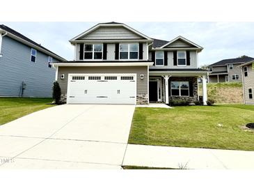 Charming two-story home featuring a spacious driveway and a manicured lawn with stone accents on the facade at 324 Bishop Ln, Sanford, NC 27330