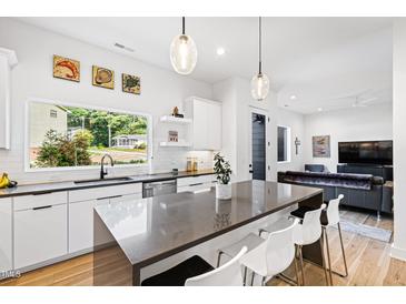 Bright, modern kitchen featuring a large island, white cabinets, stainless steel appliances, and an open layout at 1511 Malta Ave, Raleigh, NC 27610