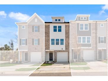Modern three-story townhome with brick and siding, featuring an attached garage and well-maintained landscaping at 2038 Fishamble St, Fuquay Varina, NC 27526