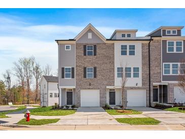 Modern townhouse with brick and gray siding, featuring a two-car garage and manicured lawn at 2042 Fishamble St # 32, Fuquay Varina, NC 27526