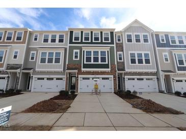 New townhomes showcasing varied exterior colors, stone accents, garages, and driveways at 2337 Bay Minette Sta # 553, Apex, NC 27502