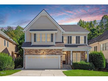 Charming two-story home featuring a stone facade, attached two car garage, and manicured landscaping at 8406 Wheatstone Ln, Raleigh, NC 27613